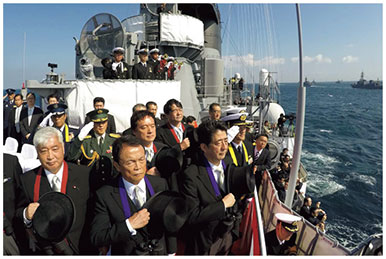 観艦式において登舷礼（とうげんれい）を受ける（前列右より）安倍内閣総理大臣、麻生副総理、中谷防衛大臣の画像