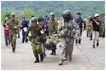 日米共同統合防災訓練（TREX）において、負傷者を米軍機へ搬送する日米の隊員の画像